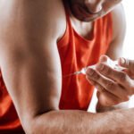 cropped view of bearded sportsman making doping injection