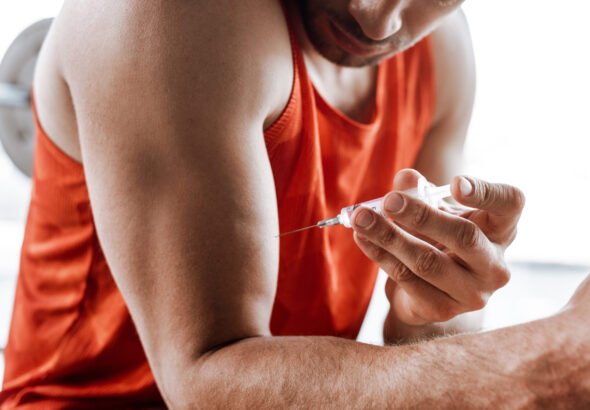cropped view of bearded sportsman making doping injection