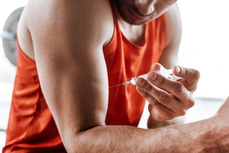 cropped view of bearded sportsman making doping injection